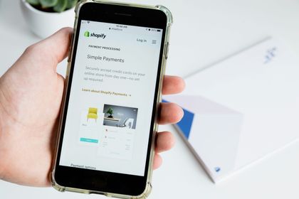 hand holding a mobile phone opened to shopify